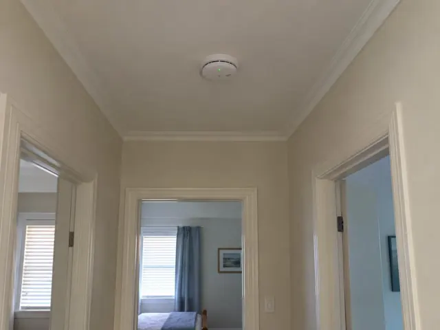 Ceiling smoke alarm in a hallway with white trim and bedroom doorways in Merewether