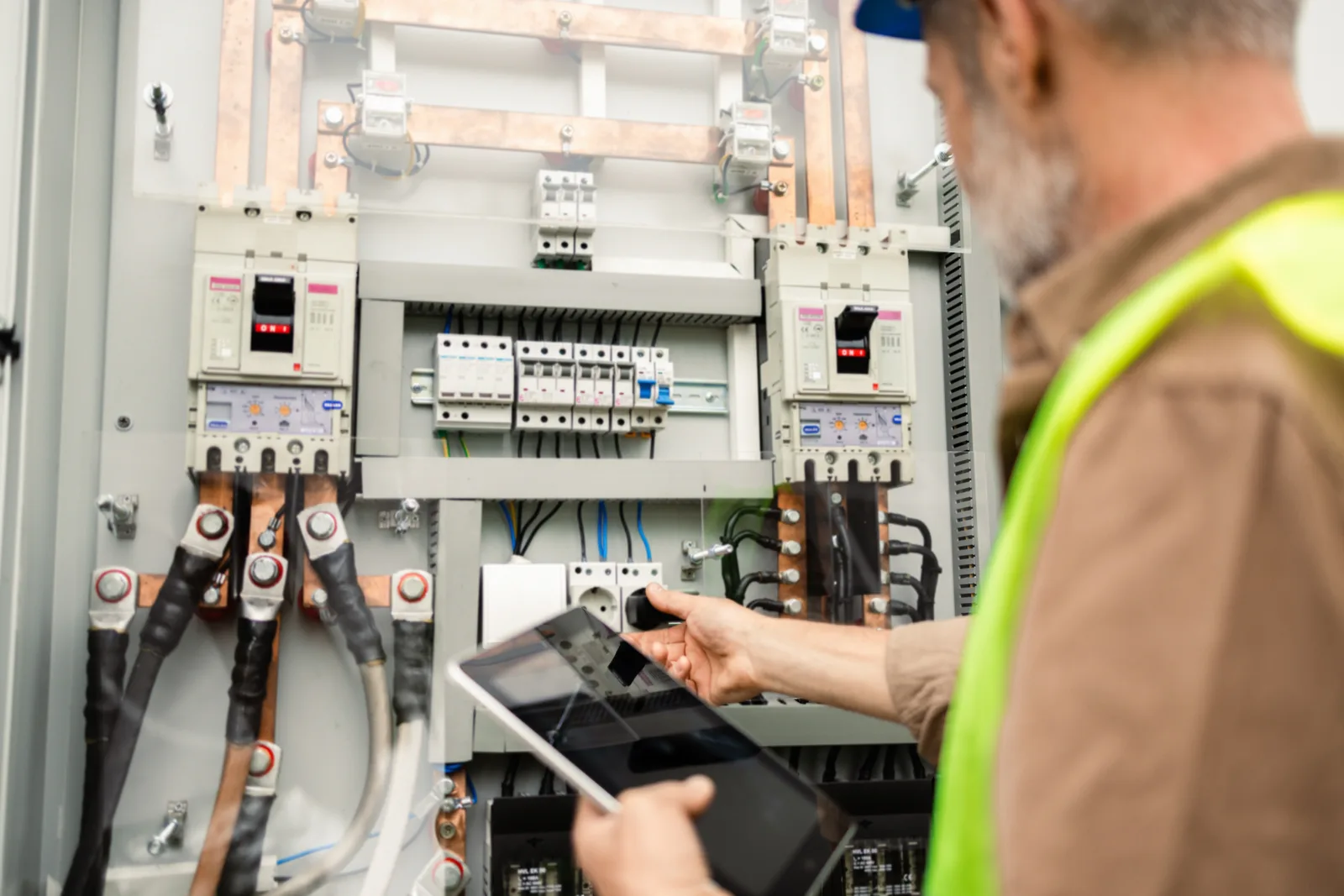 Electrician fault-finding at a switchboard with a tablet